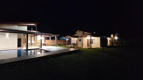 Vista nocturna del jardín, la piscina y los dormitorios iluminados