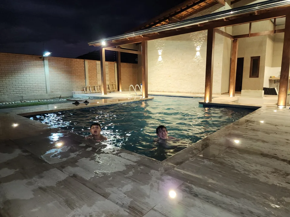 Amigos disfrutando de la piscina iluminada por la noche