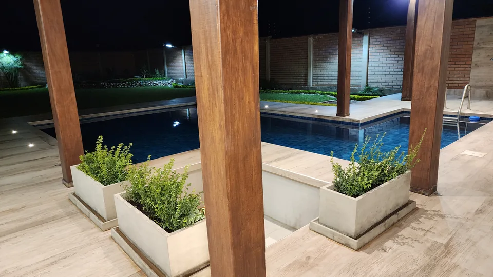 Piscina nocturna vista entre las columnas de madera de la galería